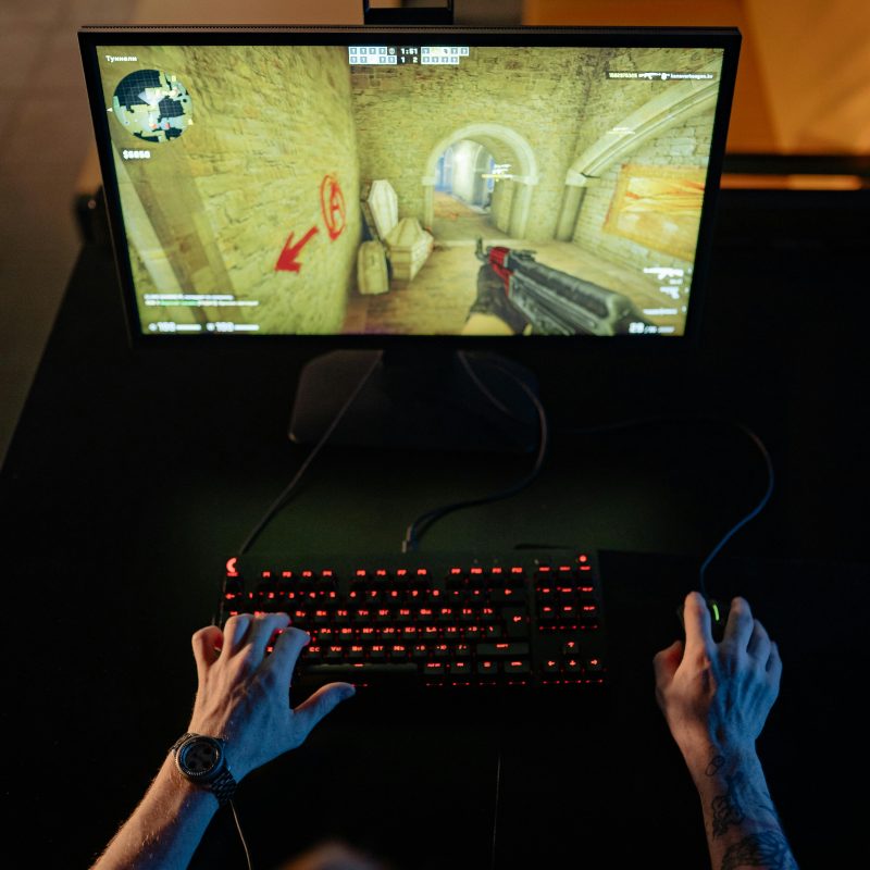 Top view of a gamer playing a video game on a computer with glowing keyboard.